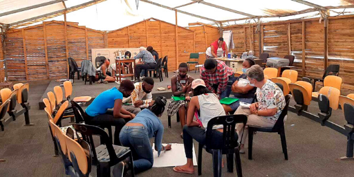 Three groups of South Africans, of different ages and genders, gather around poster boards to collaborate